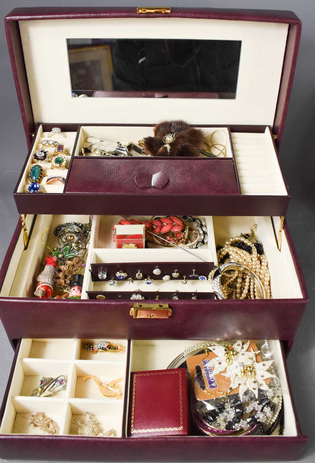 A jewellery box containing costume jewellery to include rings, charms, bracelets, Scottish grouse