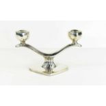 A white metal double candlestick of curved branch form set with two square sconces, with reeded stem