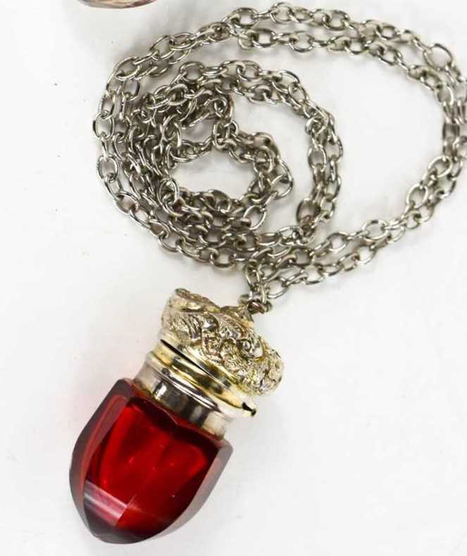 A Victorian acorn form vinaigrette, circa 1890, in red glass and gilt interior with metal chain.