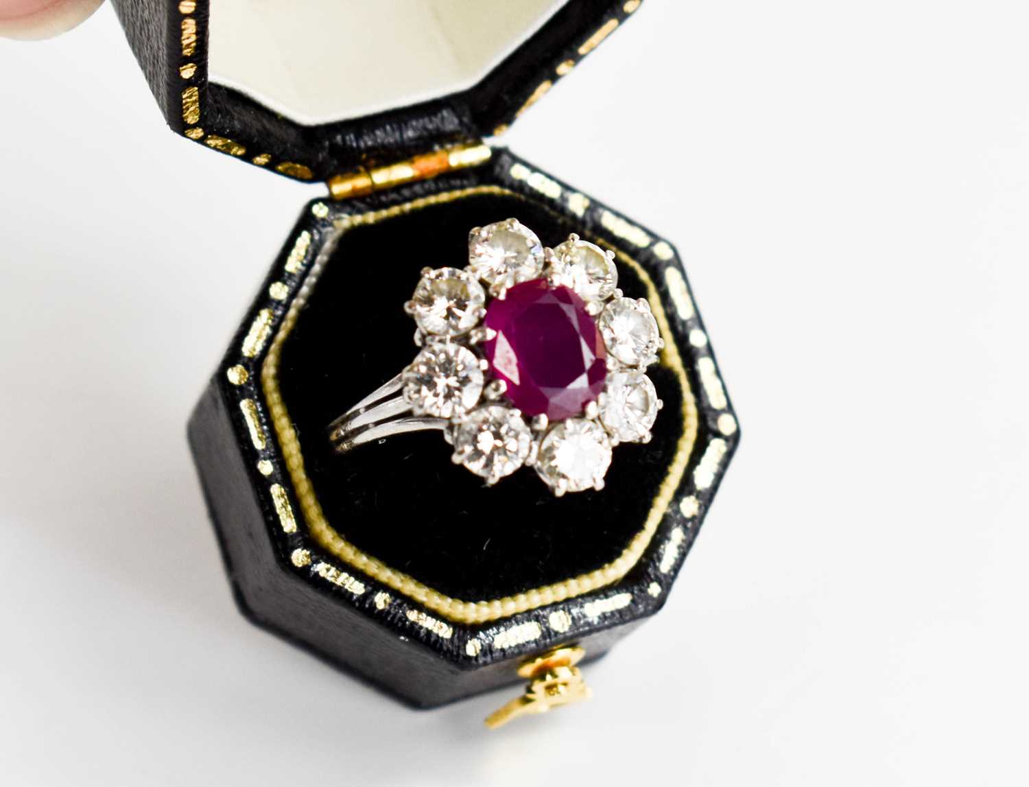 An 18ct white gold, (unmarked but tested as 18ct) ruby and diamond flowerhead ring, the central oval