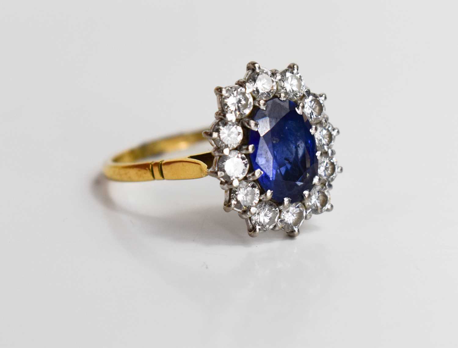 An 18ct gold, sapphire and diamond, flowerhead ring, the oval cut deep cornflower blue stone of - Image 3 of 6