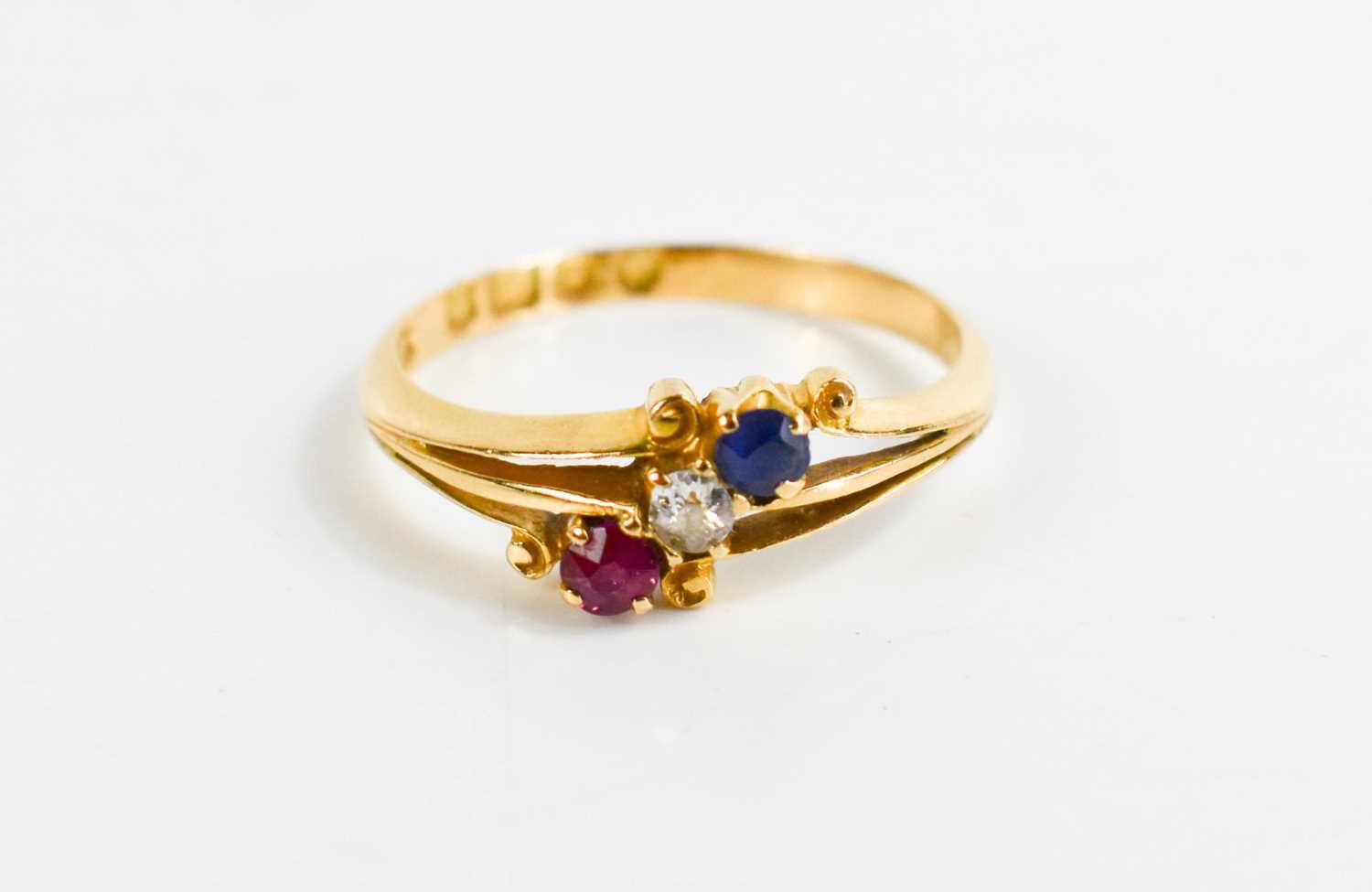 An 18ct gold, diamond, ruby and sapphire ring, the three stones in crossover scroll setting, size M,