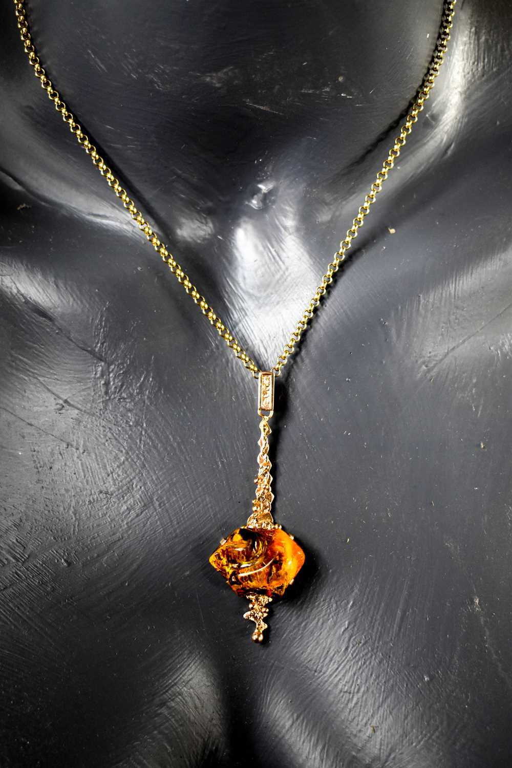 A 14ct rose gold and amber pendant, of contemporary design, on a 9ct gold chain link necklace, 7.