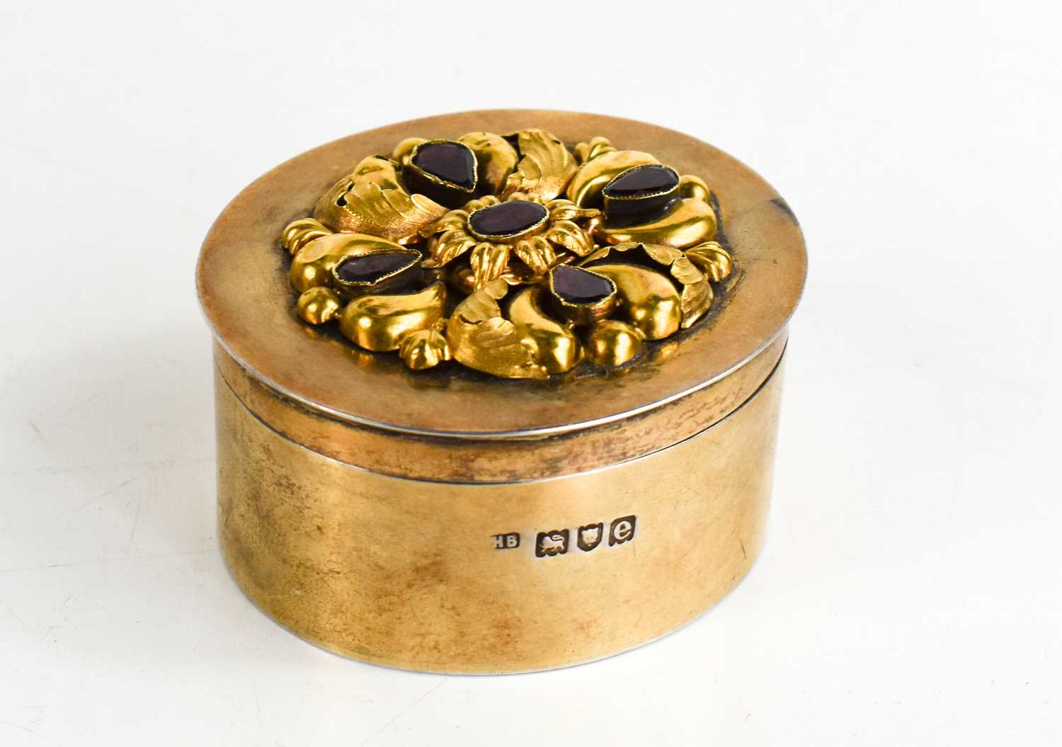 An oval silver gilt box,London 1900, the cover with earlier applied yellow metal scrollwork and four