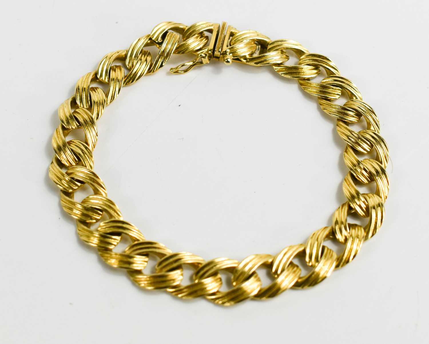 An 18ct gold flat curb link bracelet with reeded detail, 21cm long, 32.93g.