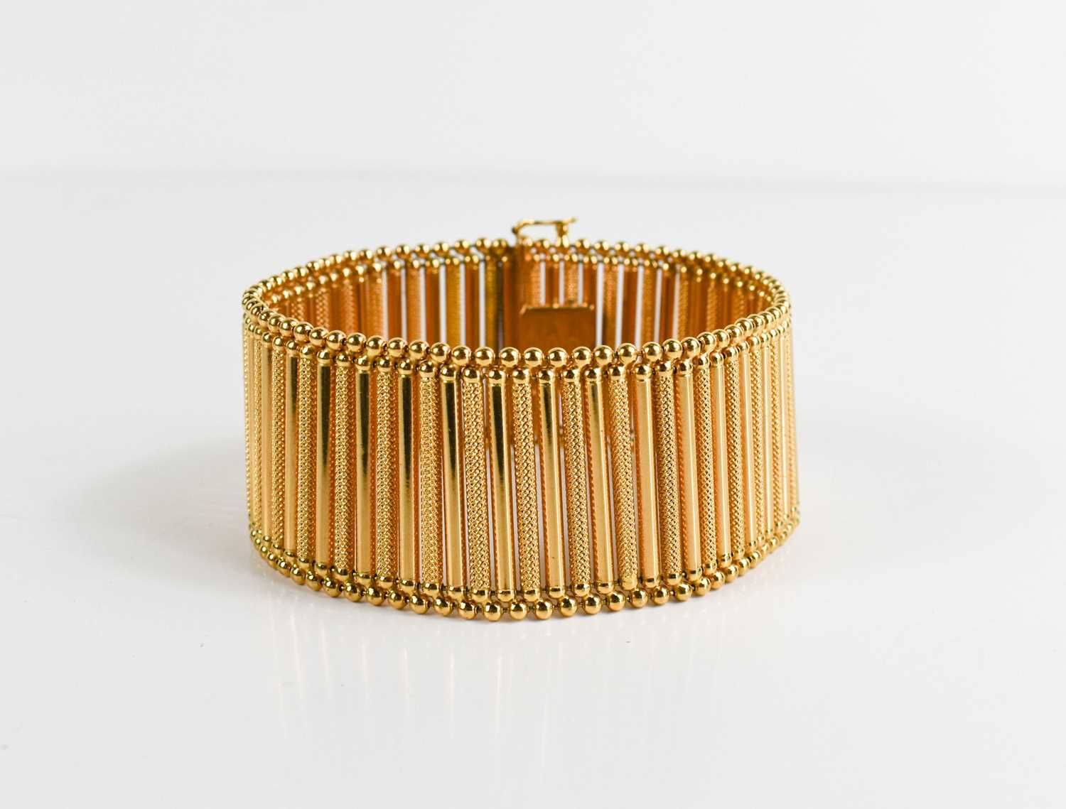 An 18ct gold bar link bracelet, plain links interspersed with machine engraved decoration, slide