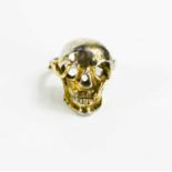 An unusual vintage silver gilt ring, finely modelled as a skull with a snake writhing through the