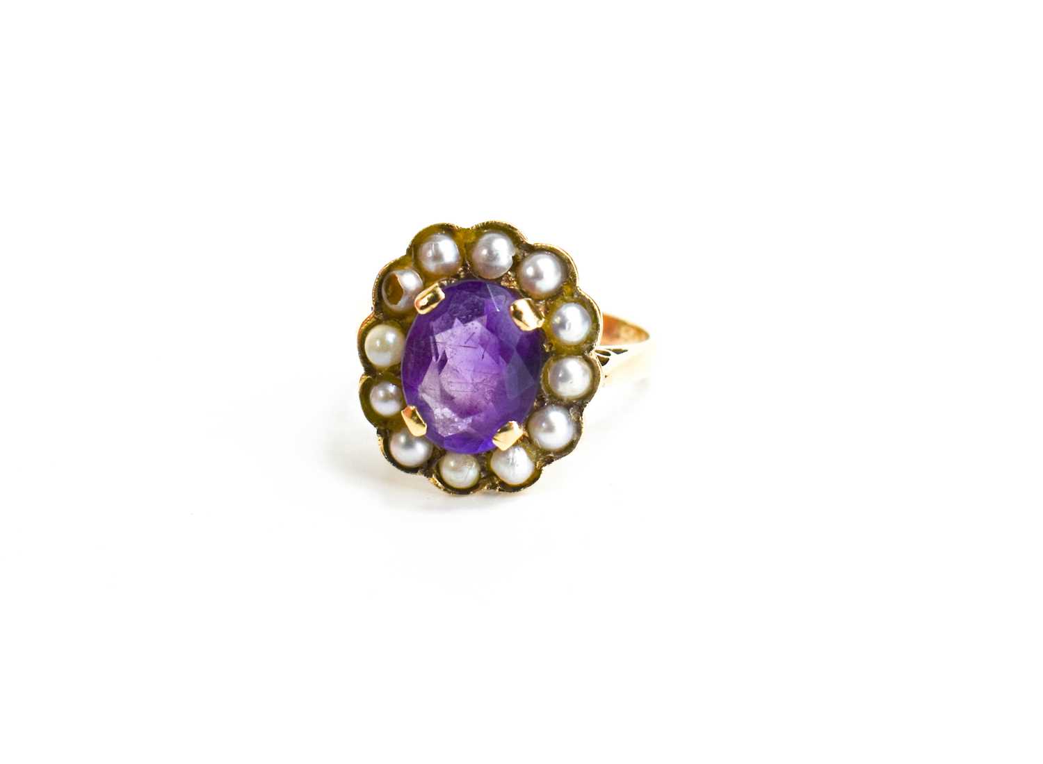 A 9ct gold, amethyst and seed pearl ring, the oval cut amethyst 10mm by 7mm, bordered by seed