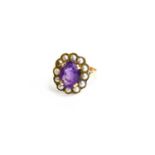 A 9ct gold, amethyst and seed pearl ring, the oval cut amethyst 10mm by 7mm, bordered by seed