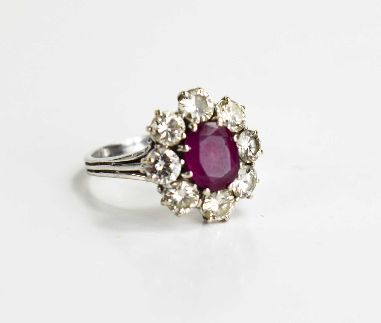 An 18ct white gold, (unmarked but tested as 18ct) ruby and diamond flowerhead ring, the central oval - Image 7 of 11