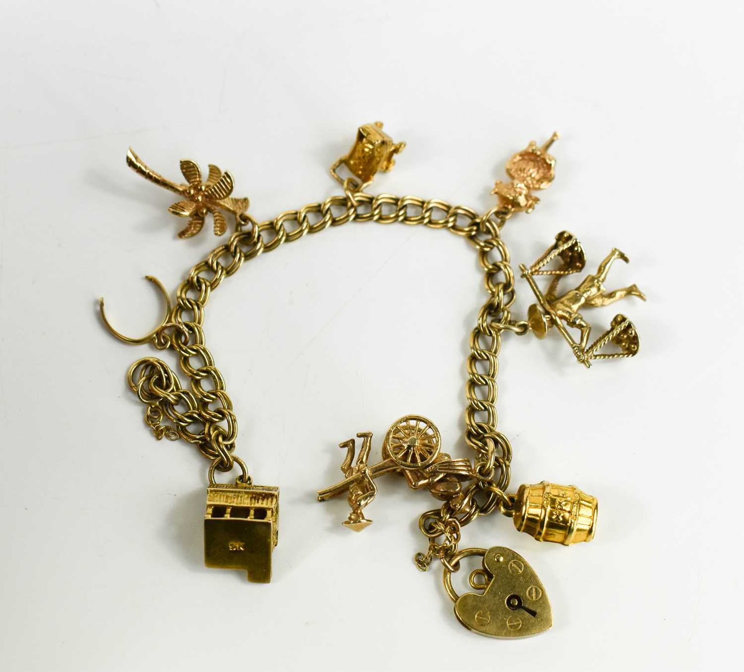 A fine double curb link 9ct gold charm bracelet with eight charms, including some Chinese