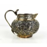 An Indian white metal, likely silver although unmarked jug, ornately decorated with an wild