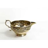 A Victorian small silver cream jug, of cup form, chased with flowers and scallop shells, with curled