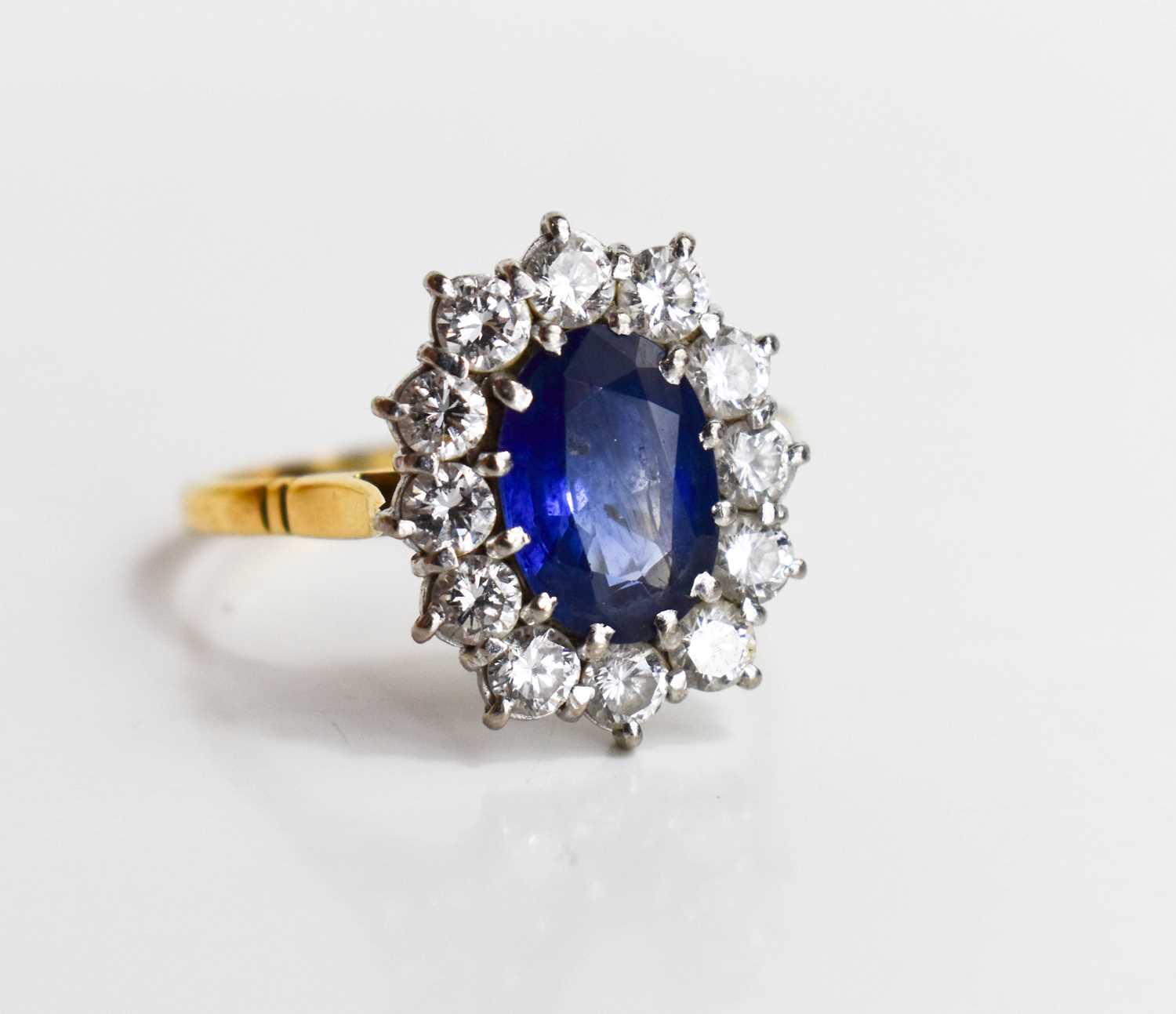 An 18ct gold, sapphire and diamond, flowerhead ring, the oval cut deep cornflower blue stone of