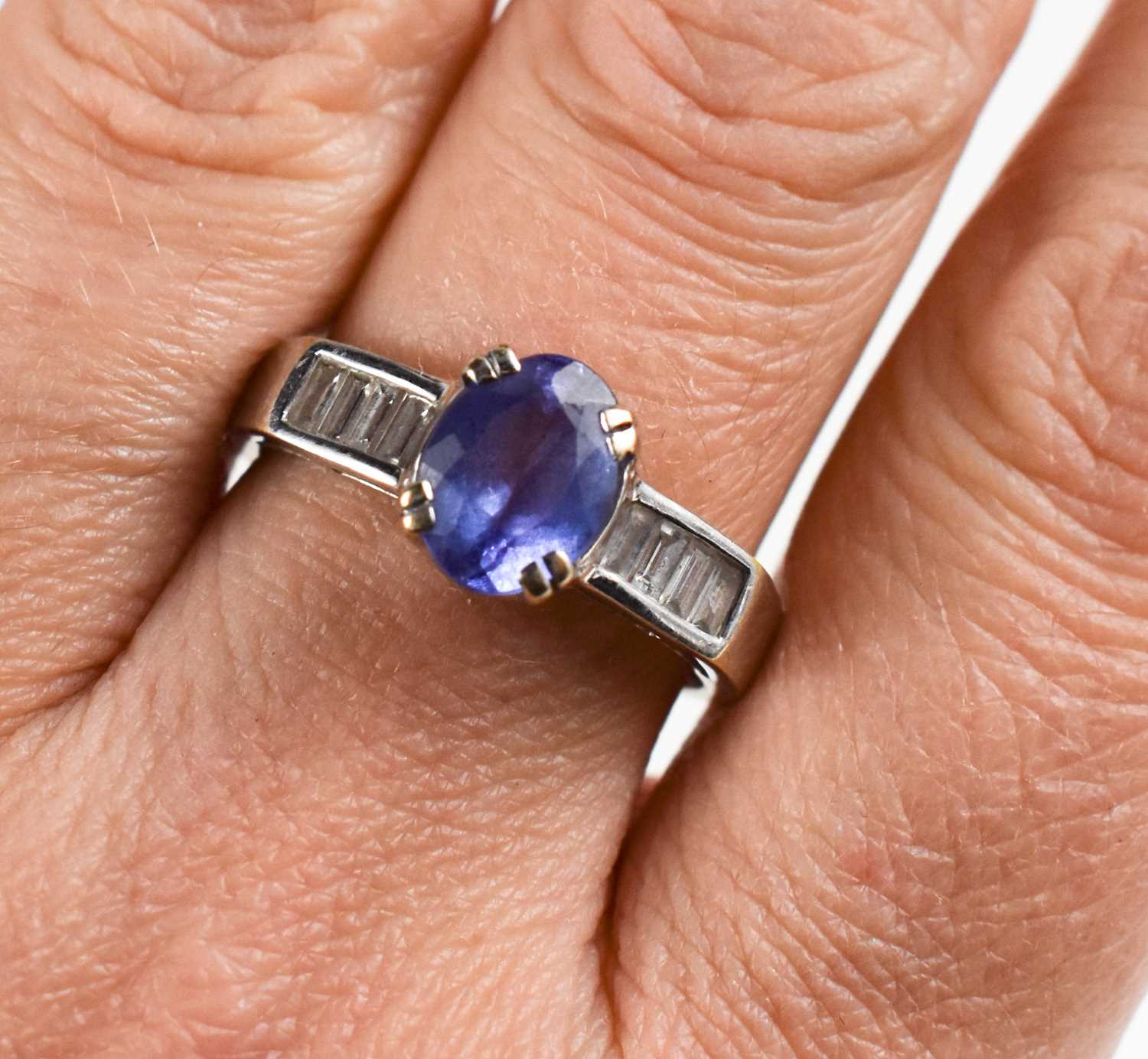 An 18ct white gold, tanzanite and diamond ring, the oval cut tanzanite flanked by baguette cut