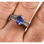 An 18ct white gold, tanzanite and diamond ring, the oval cut tanzanite flanked by baguette cut