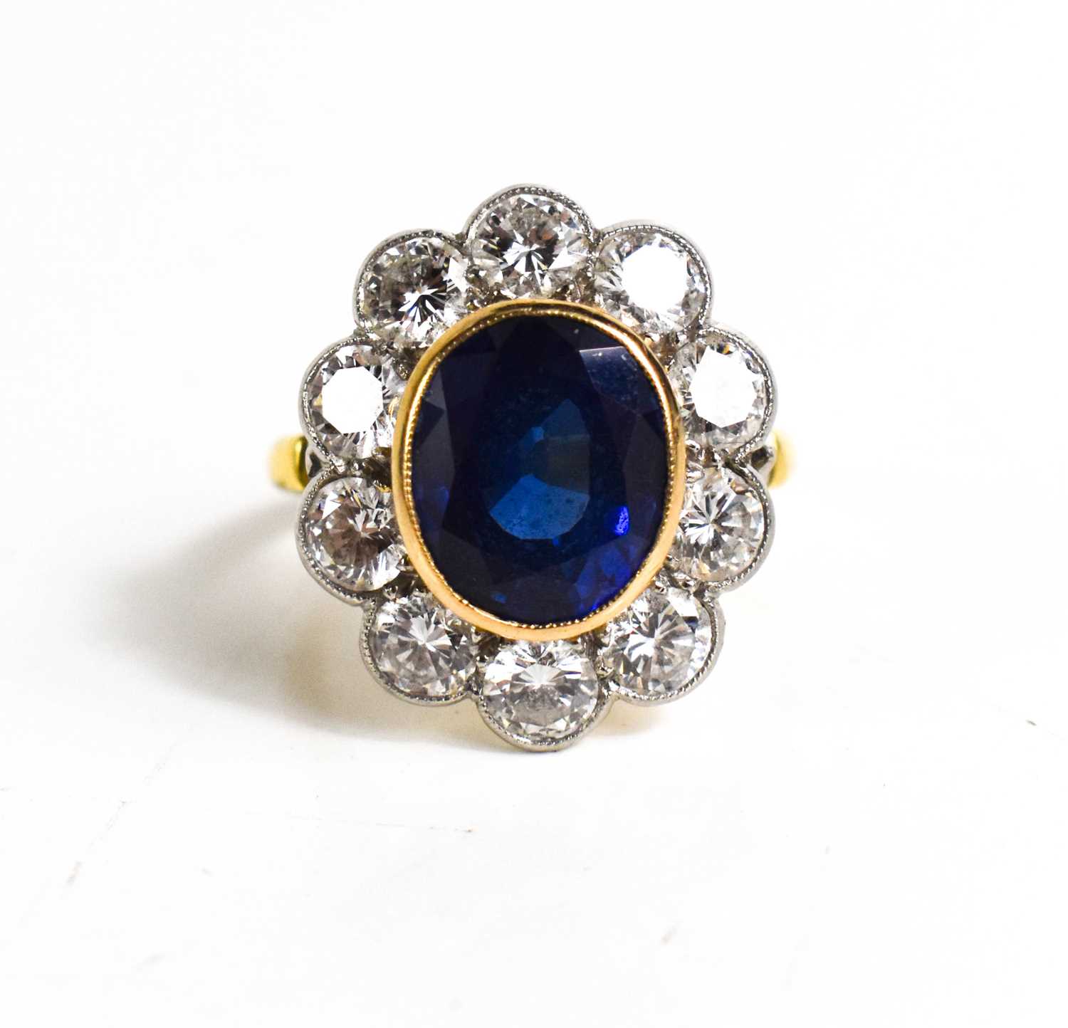 An 18ct yellow gold, sapphire and diamond ring, the central oval cut deep cornflower blue sapphire