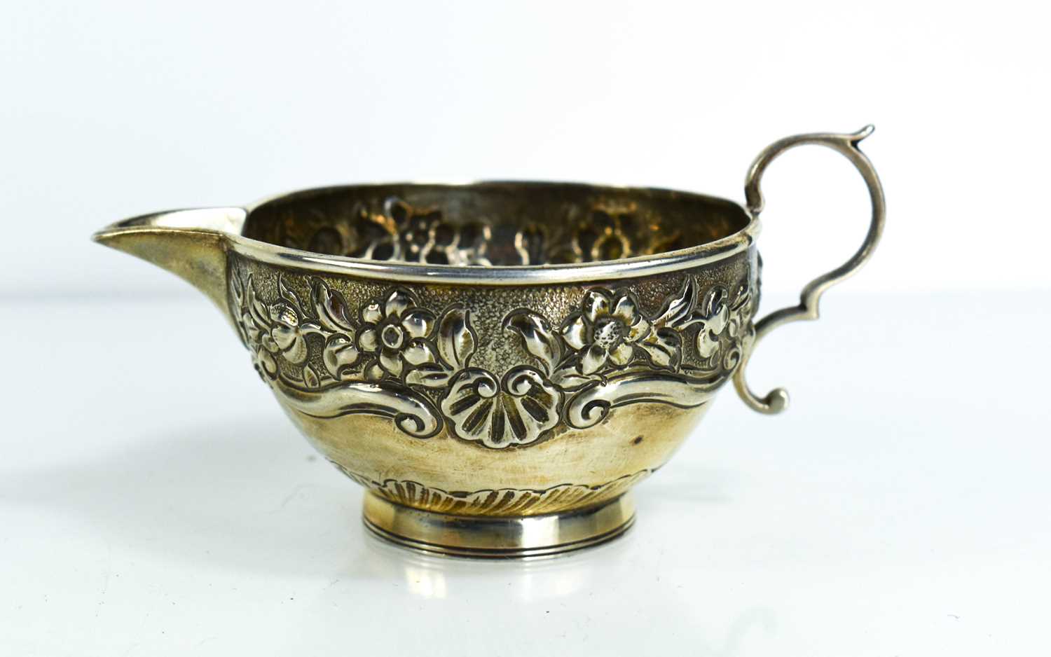 A Victorian small silver cream jug, of cup form, chased with flowers and scallop shells, with curled - Image 2 of 2