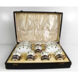 A cased set of Royal Worcester coffee cans and saucers, puce mark 1900, decorated with green and
