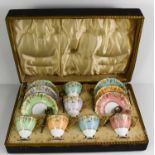 A cased set of Royal Crown Derby tea cups and saucers, in a variety of colours, shaped with vine
