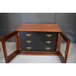 An Edwardian mahogany collectors cabinet with ebonised interior drawers enclosed by glass doors.