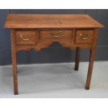 A 19th century oak lowboy with three drawers, a shaped apron front, raised on chamfered legs, 89
