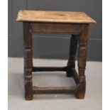 A 17th century oak joint stool, the slab top raised on turned legs with peripheral stretchers,