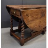 A 18th century oak drop leaf table, the oval top having two leaves which fold out onto bobbin turned