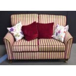 An Anvils of Stamford Courtney two seater accent sofa with mahogany feet and brass castors, 138cm