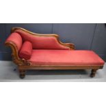 A late 19th century chaise longue, with carved mahogany frame, shaped back, raised on baluster legs,