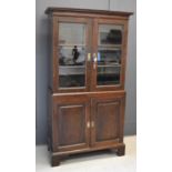 An early 19th century mahogany cabinet, the upper section with glazed doors, the lower section