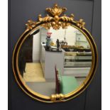A large and impressive circular mirror, in the French Empire style, with gilded foliate pediment and