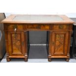 An oak kneehole desk, the twin pedestals with cupboards below three drawers, all with burr walnut