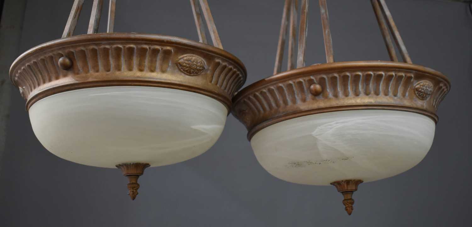 A pair of Empire style bronze painted ceiling lights, with opaque domed glass shades, together