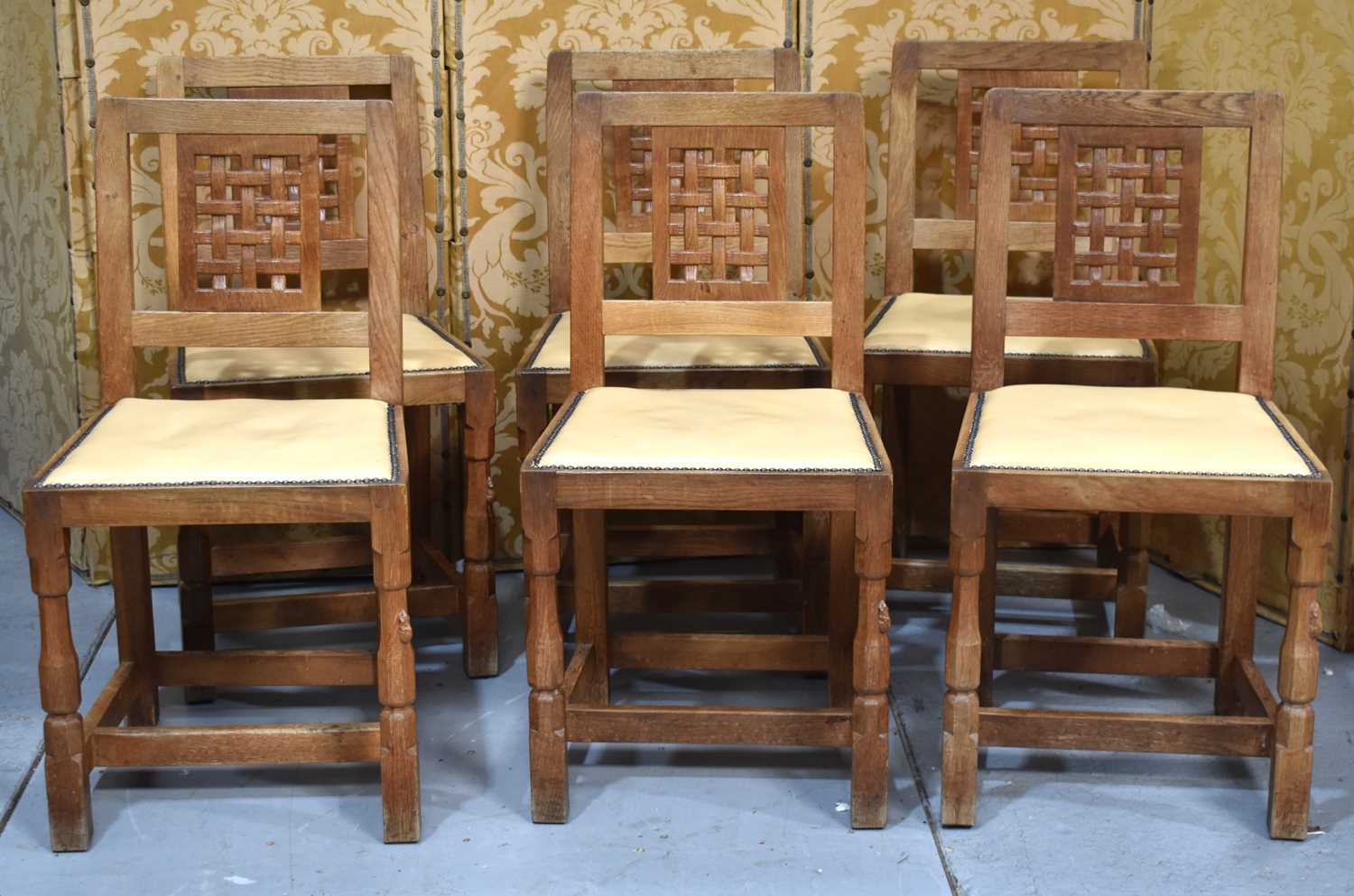 A set of six Robert "Mouseman" Thompson oak lattice back dining chairs with cow hide seats, on two