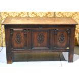 A large early 20th century oak coffer in the Arts and Crafts style, the front carved in three panels