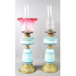A pair of 19th century glass oil lamps, the celeste blue ceramic bodies hand painted above Art