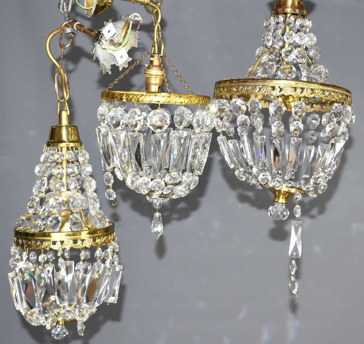 A group of three cut glass and gilt metal chandeliers, comprising one of bag form and two Empire