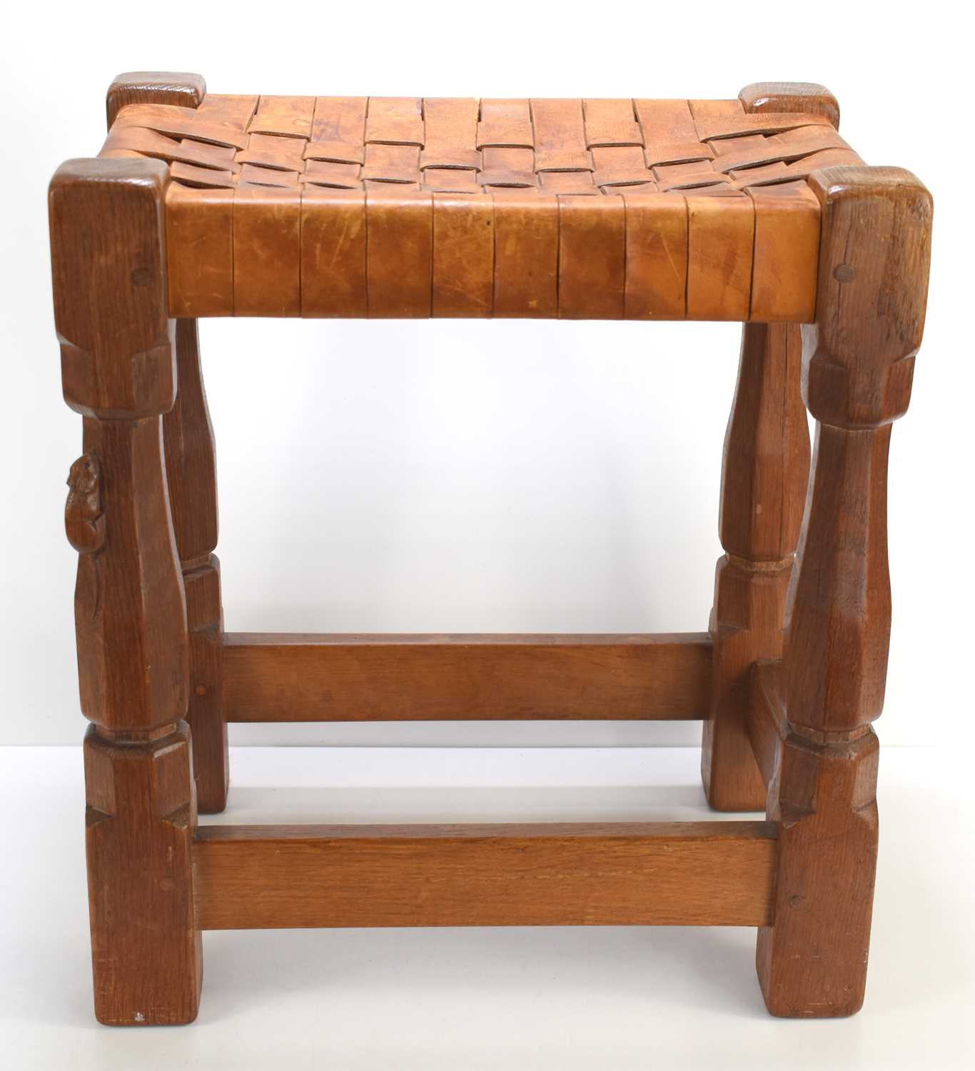 A Robert "Mouseman" Thompson oak stool with intertwined leather seat, with carved mouse to the