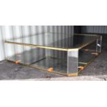 A large and impressive modernist low coffee table with gold coloured metal frame united with a glass