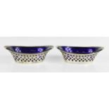 A pair of silver and blue glass lined salts, the silver cases pierced with decoration, and