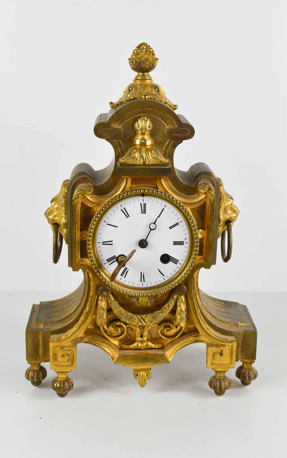 A French 19th century gilt metal mantle clock, with enamel Roman Numeral dial, and two lion head and