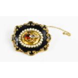 A Victorian mourning brooch, the rococo scroll border with black enamel band to seed pearls