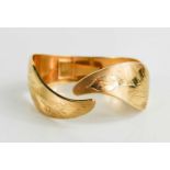 An 18ct gold bangle, engraved with foliage and shaped in the form of leafy fronds, 30g.