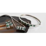 A 14ct white gold, diamond and emerald demi parure, consisting a bangle set with seven baguette