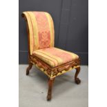A scroll back Victorian nursing chair, with carved frame and hairy paw feet raised on casters,