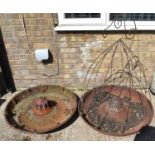 Two cast iron Mexican hat pig troughs, one with metal frame work.