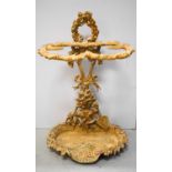 A cast iron stick stand, the back cast with wheat sheaf and hand tools, and painted cream.