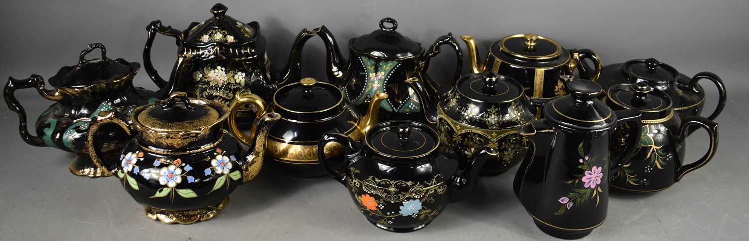 A large collection of Jackfield pottery teapots, including one of oval form with Japanese