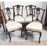 A set of four mahogany dining chairs with intricately carved and pierced splats, and cream